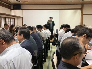 長い机の両側に会員の不動産会社の皆さまが並び、奥で当センター代表が講演している会場の様子