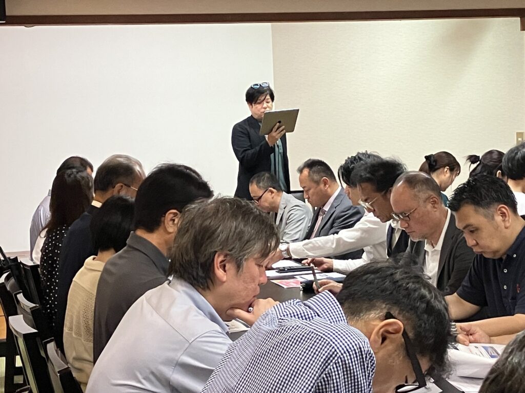 タブレットを手に講演する当センター代表の元佑也と、資料を読む参加者の皆さま